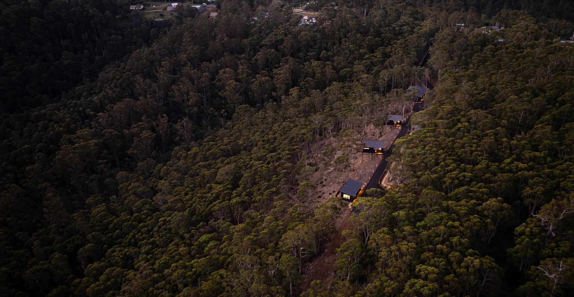 Aerial view of the Breath cabins nestled among the forested hills of Fern Tree, Tasmania.